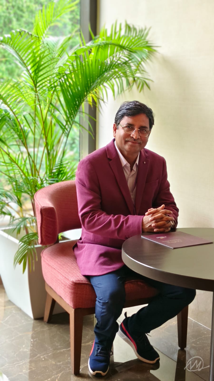 Sashikanta Malik, Self-Worth & Dignity Coach, seated in a magenta blazer